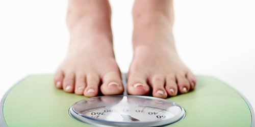 Pessoa se pesando em uma balança. O que é dieta cetogênica?