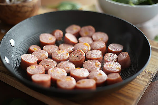 Cooking sliced sausages.