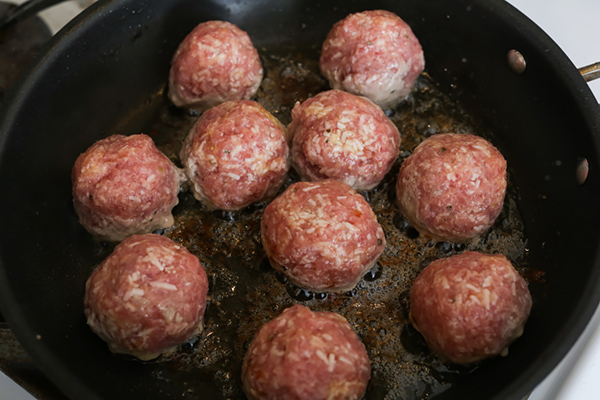 Cooking meatballs in a frying pan.