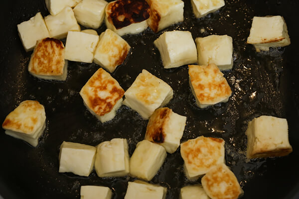 Halloumi frying in a pan.