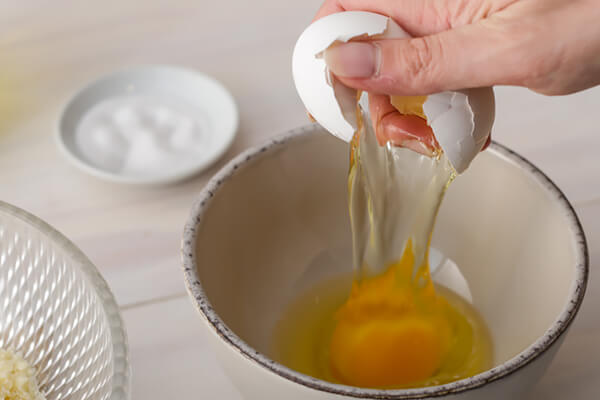 Cracking eggs open into a bowl.