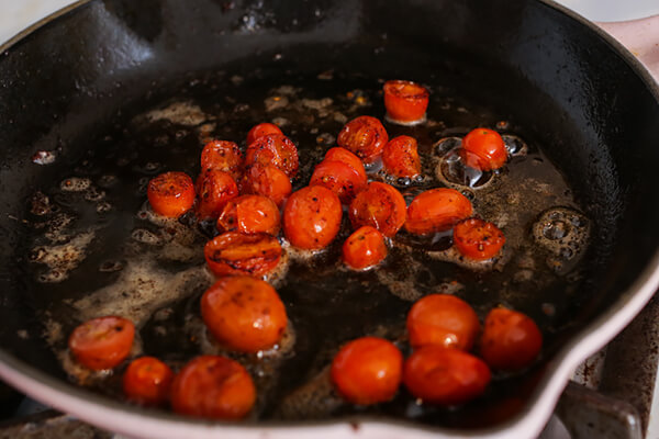 Cherry tomatoes roasting in a skillet.