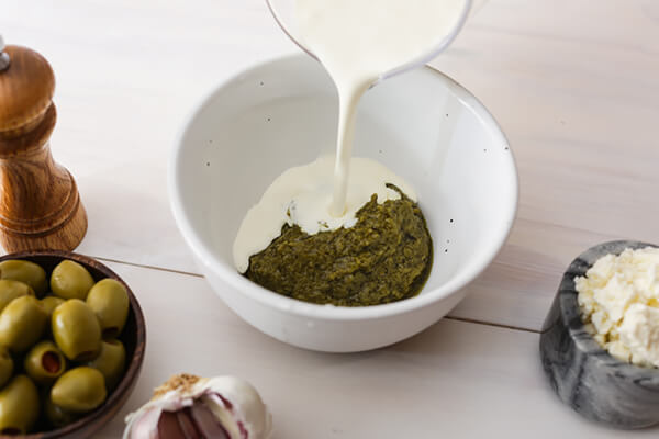 Mixing pesto and heavy cream together.