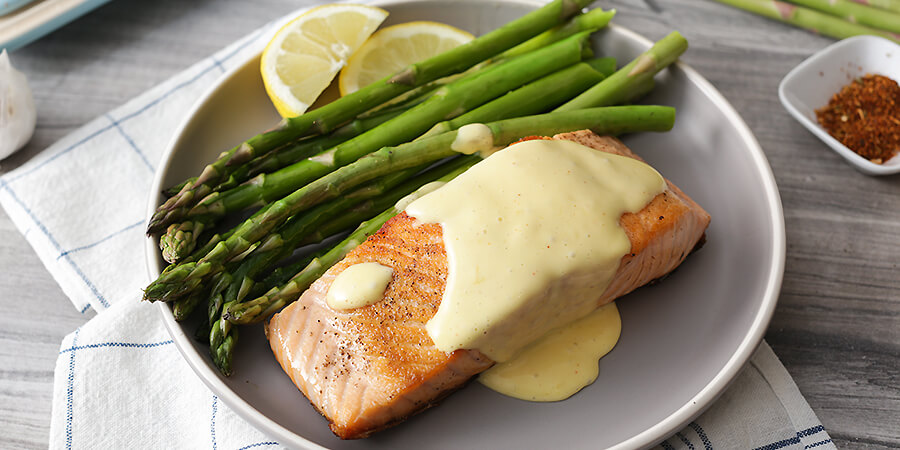 Seared salmon and asparagus spears with hollandaise sauce on top.