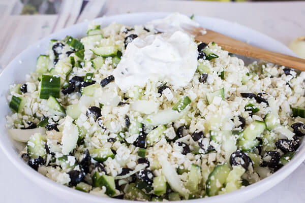 Salad with dollop of tzatziki on top of it.