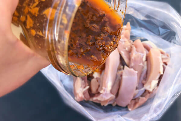 Pouring marinade on chicken.